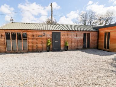 A wooden building with a dark door and windows on a gravel area at Kelyow in St Day