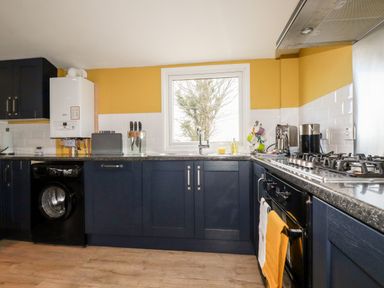 A kitchen with dark cabinets and a window above the sink at Kelyow in St Day