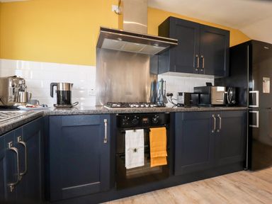 A kitchen with dark cabinets a stove oven refrigerator and various appliances on the countertops at Kelyow in St Day