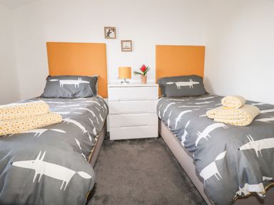 A bedroom with two single beds with orange headboards and animal print bedding at Kelyow in St Day