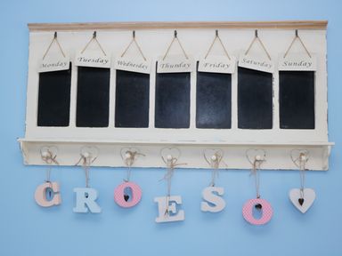 A weekly wall organizer with blackboards for each day and hanging letters spelling croeso at Hen Stabl in Llanrwst