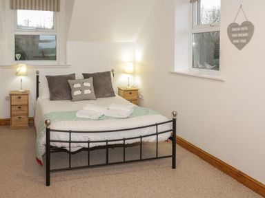 A bedroom with a double bed between two wooden bedside tables with lamps at Hen Stabl in Llanrwst