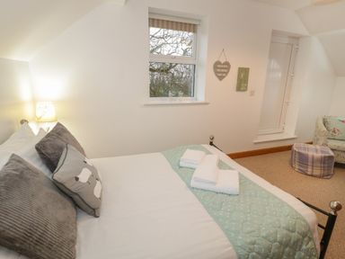 A bedroom with a bed with folded towels on a light blue quilt and pillows with sheep designs at Hen Stabl in Llanrwst