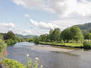 A river with trees and hills in the background at Hen Stabl in Llanrwst