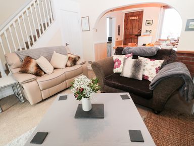 A living room with two sofas and a table with flowers at Corbett Cottage in New Haggerston near Holy Island