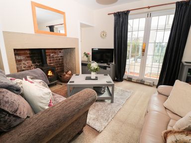 A living room with sofas a coffee table a fireplace and a television at Corbett Cottage in New Haggerston near Holy Island