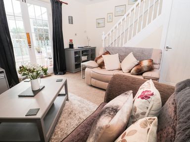 A living room with two sofas a coffee table with a flower vase and framed pictures on the wall at Corbett Cottage in New Haggerston near Holy Island