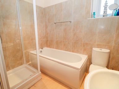 A bathroom with a shower cubicle bathtub toilet and sink at Corbett Cottage in New Haggerston near Holy Island