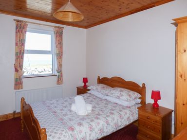 A bedroom with a wooden bed and bedside tables with red lamps at Seaview Cottage in Fanore County Clare