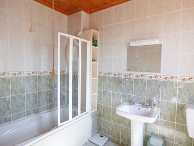 A bathroom with a bathtub shower combo sink mirror and scale at Seaview Cottage in Fanore County Clare