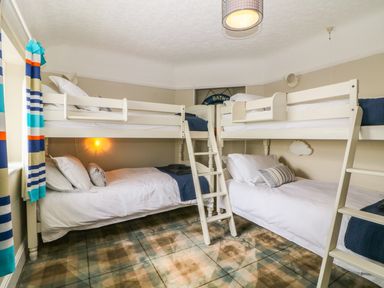 A bedroom with two sets of white bunk beds and plaid carpet at The Beach House Criccieth