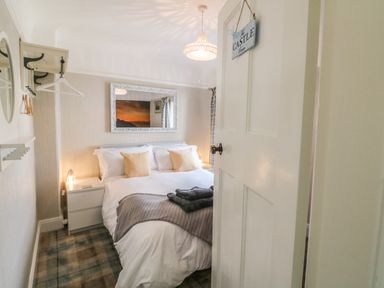 A bedroom with a double bed pillows bedside tables and a mirror above the bed at The Beach House Criccieth