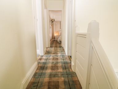 A hallway with plaid carpet leading to a bedroom at The Beach House Criccieth