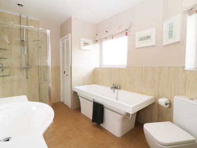 A bathroom with a bathtub a toilet a shower cubicle and a washbasin at The Beach House Criccieth in Criccieth