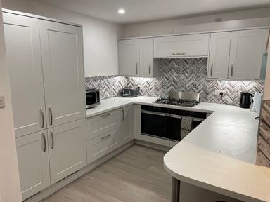A kitchen with white cabinets a microwave toaster and kettle at The Beach House Criccieth
