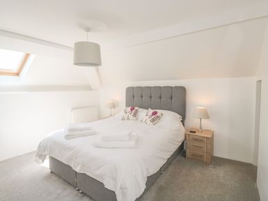 A bedroom with a bed, bedside tables with lamps, and a skylight window at Lower West Curry Cottage in Launceston