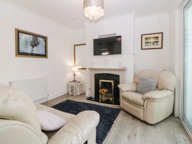 A living room with leather armchairs a fireplace and a mounted TV at Pier View in Paighton