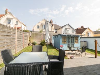 A garden with outdoor furniture and a blue garden shed at Pier View in Paighton