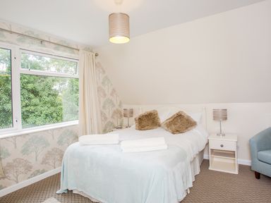 A bedroom with a bed side tables lamps and a window with curtains at Dartmoor View in Gunnislake