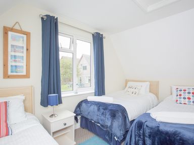 A bedroom with three single beds blue curtains and a nightstand with a lamp at Dartmoor View in Gunnislake