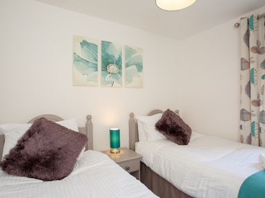 A bedroom with two single beds a bedside table with a lamp and wall art at Dartmoor View in Gunnislake
