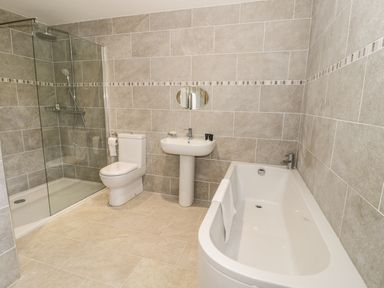 A bathroom with a bathtub a shower a toilet and a sink at Rede River Cottage in West Woodburn