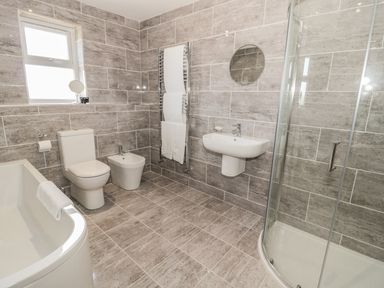 A bathroom with a bathtub toilet bidet sink shower and a window at Rede River Cottage in West Woodburn