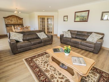 A living room with two brown sofas a wooden coffee table and a dining area at Rede River Cottage in West Woodburn