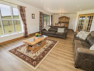 A living room with two sofas a wooden coffee table and dining area at Rede River Cottage in West Woodburn