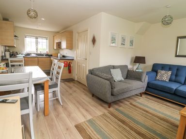 An open plan living room and kitchen with dining table chairs sofas and a striped rug at 104 Sunrise Drive in Filey