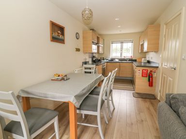 A kitchen and dining area with a table and chairs and wooden cabinets at 104 Sunrise Drive in Filey