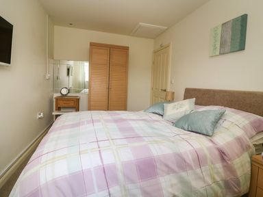 A bedroom with a bed a wardrobe a bedside table and a wall-mounted television at 104 Sunrise Drive in Filey