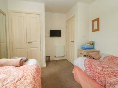 A bedroom with two single beds a small television on the wall and a bedside table with books at 104 Sunrise Drive in Filey
