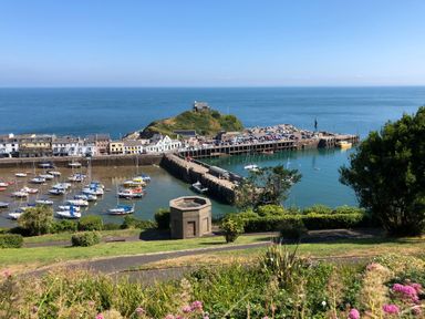 A harbor with boats docked near a village and a hill with a building near the ocean at 10 Oceanside in Ilfracombe