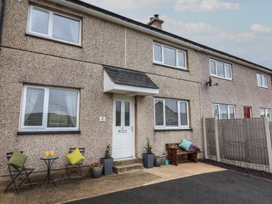 A pebble dash house front with a white door two windows and outdoor seating at Gwynfa in Rhyd Uchaf near Bala Gwynedd