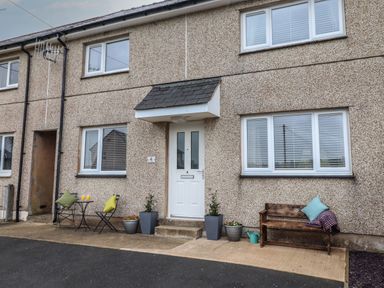 The front of a house with a white door two windows outdoor seating and potted plants at Gwynfa Rhyd Uchaf near Bala Gwynedd