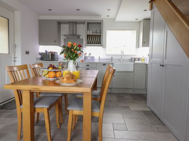A kitchen with a wooden dining table and chairs with fruit and flowers on the table at Gwynfa in Rhyd Uchaf near Bala Gwynedd