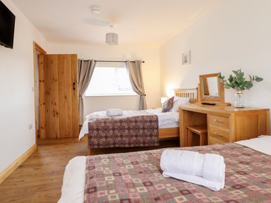 A bedroom with two single beds a wooden dressing table a window and a wooden door at Gwynfa in Rhyd Uchaf near Bala Gwynedd