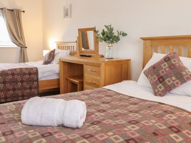 A bedroom with two single beds a wooden dressing table with a mirror and a vase with leaves at Gwynfa in Rhyd Uchaf near Bala Gwynedd