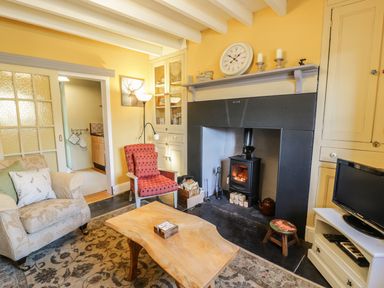 A living room with armchairs a wooden coffee table and a fireplace at Miners Cottage in Blaenau Ffestiniog