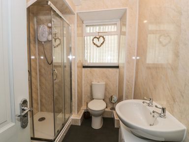 A bathroom with a shower cubicle a toilet and a sink at Miners Cottage in Blaenau Ffestiniog