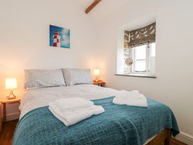 A bedroom with a double bed blue throw folded towels on the bed and two bedside lamps at Snowdrop Cottage in Llantwit Major