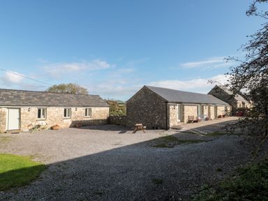 A courtyard with stone buildings and outdoor benches at Snowdrop Cottage in Llantwit Major