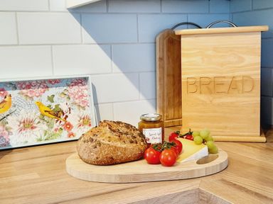 A kitchen with bread and cheese on a cutting board at Crab Cottage in Ilfracombe