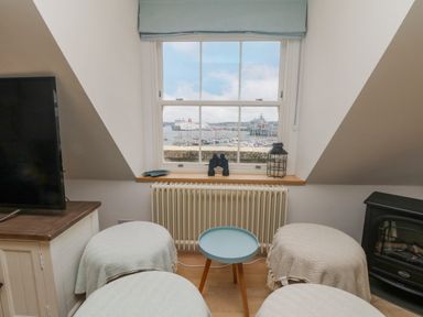 A small seating area with a window overlooking boats and ships at Dawn Catcher in Falmouth