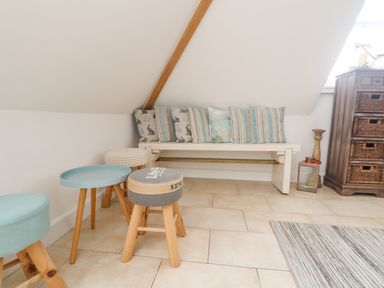 A seating area with a bench and stools under a slanted ceiling at Dawn Catcher in Falmouth