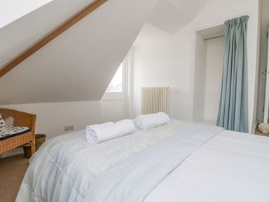 A bedroom with a bed with rolled towels and an open closet with a curtain in Dawn Catcher in Falmouth
