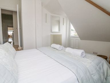 A bedroom with a bed with rolled towels on it and a window under a slanted ceiling at Dawn Catcher in Falmouth