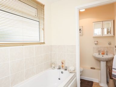 A bathroom with a bathtub and a small adjoining room with a sink and toilet at The Cabin in Combe Martin