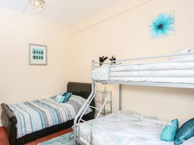 A bedroom with a single black bed and a metal bunk bed with blue and white bedding at The Cabin in Combe Martin